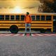 High School Student Standing in front of a school bus