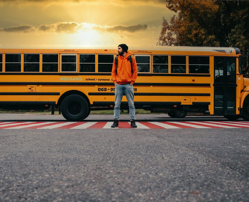 High School Student Standing in front of a school bus